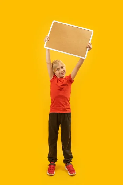 티셔츠를 금발의 소년이 코르크 참기를 손으로 종이와 아이의 스튜디오 수직적 — 스톡 사진