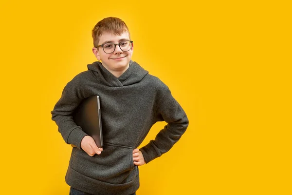 Підлітковий Школяр Повсякденному Одязі Окулярах Тримає Ноутбук Посміхається Жовтому Тлі — стокове фото