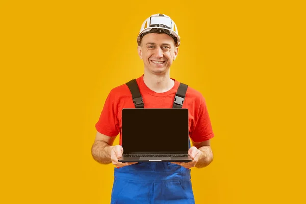 中年建筑师工程师戴着安全帽 手持笔记本电脑 屏幕空白 背景是黄色的工作室 复制空间 — 图库照片