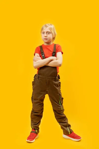 全长的金发碧眼的男孩的肖像在明亮的黄色背景工作服 垂直框架 — 图库照片