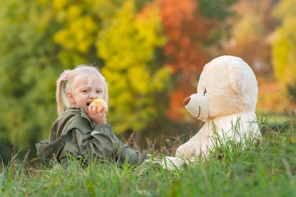 Ευτυχισμένο Κοριτσάκι Τρώει Μήλο Και Παίζει Μεγάλο Αρκουδάκι Κάθεται Στο — Φωτογραφία Αρχείου
