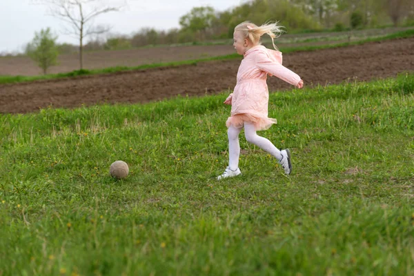 穿着粉红衣服的小女孩跑过绿色的草地 踢着球 田里的孩子们在嬉戏 — 图库照片