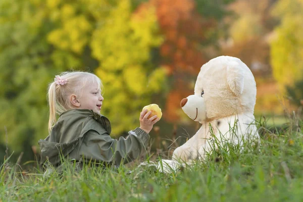 Красива Дівчинка Грає Великим Плюшевим Ведмедем Сидячи Траві Тлі Осіннього Ліцензійні Стокові Фото