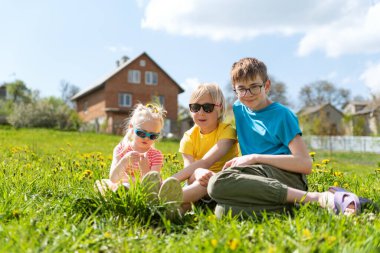 Mutlu bir çocukluk. Karahindiba çiçeğinin üzerine çocuk kardeşler oturur. Yaz tatili.