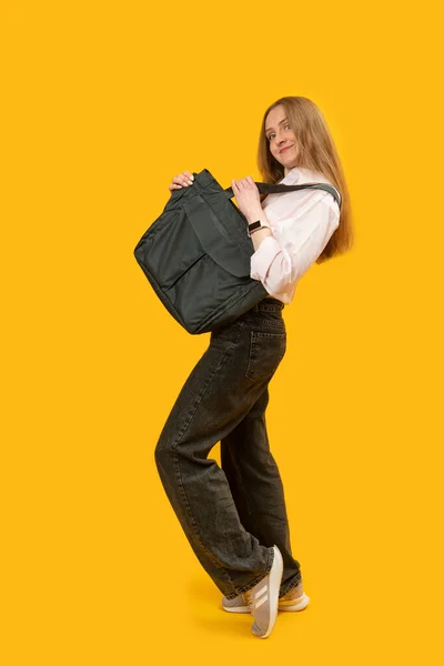 Smiling young woman with black purchasing bags on yellow background. Eco-friendly shopper bag in womans hands