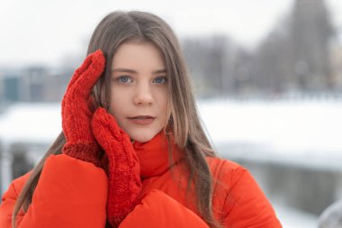 Kırmızı ceketli ve kışın eldivenli güzel bir kadının kış portresi. Gençlik giysileri..