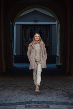 Çekici genç kadın portresi. Kış kıyafetleri ve kürk manto. Şehir sokaklarında. Soğuk mevsim, şehirde yürüyüş. Dikey çerçeve.
