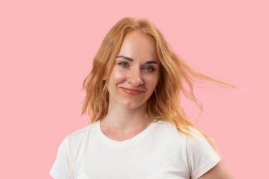 Kızıl saçlı ve kameraya bakan yeşil gözlü gülümseyen genç kadının portresi. Kendine güvenen güzel bir kadın. Pembe arkaplan.