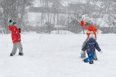 Çocuklar kartopu oynar. Çocuklar kışın kar yağarken dışarıda eğlenirler. Kış eğlencesi.