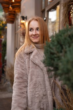 Noel süslemeleri arka planında kürk giymiş çekici bir kadın, şenlikli bir sokak. Noel havası. Hafta sonu tatili