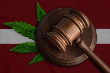 Letonya bayrağında kenevir yaprağı olan tahta tokmak. Esrar bitkisinin ve uyuşturucuların yayılmasının yasadışı büyümesi.