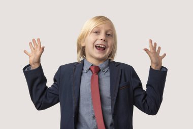 Sarı saçlı, mavi ceketli, kırmızı kravatlı ve gri gömlekli mutlu, beyaz arka planda izole edilmiş küçük bir çocuğun portresi.