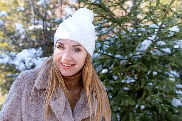 Kış portresi, kürk mantolu, beyaz örgü şapkalı, bubo kaplı, köknar ağaçlı, kızıl saçlı kızın portresi.