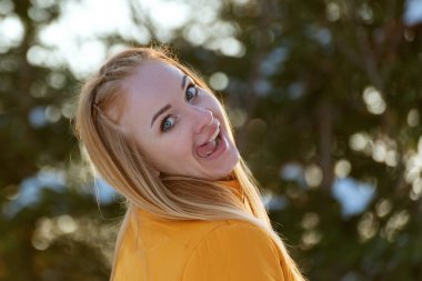 Neşeli kız kameraya surat yapar ve dilini gösterir. Dışarıdaki kızıl saçlı kadının portresi.