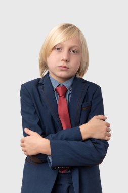 Ciddi bir şekilde kameraya bakan takım elbiseli ve kravatlı ciddi bir çocuğun portresi..