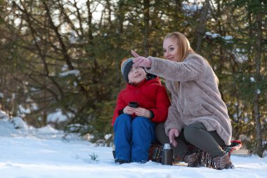 Anne ve oğlu kış ormanlarında karda oturup iletişim kuruyorlar..