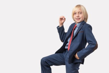 Takım elbiseli şirin bir çocuğun portresi beyaz bir arkaplanda fotokopi alanı ile poz veriyor..