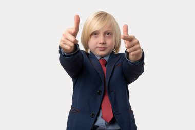 Takım elbiseli bir çocuğun portresi beyaz arka plandaki kamerayı işaret ediyor..