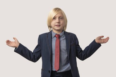 Sarışın, mavi takım elbiseli, kırmızı kravatlı, beyaz arka planda izole edilmiş şirin bir çocuk..