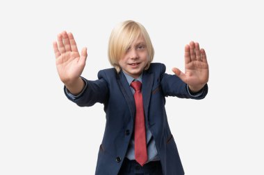 Mavi takım elbiseli şirin bir çocuğun portresi iki eliyle dur hareketi gösteriyor. Beyaz arkaplanda izole