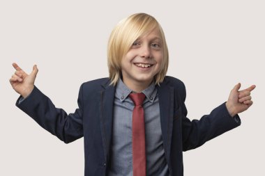 Sarı saçlı, mavi ceketli ve kırmızı kravatlı mutlu küçük bir çocuğun portresi, ellerini yana açıyor, geniş bir şekilde gülümsüyor, ilginç bir şey gördüğüne seviniyor, beyaz arka planda izole edilmiş.