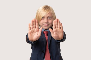 Beyaz arka planda soyutlanmış beyaz bir çocuk iki eliyle dur hareketi yapıyor..