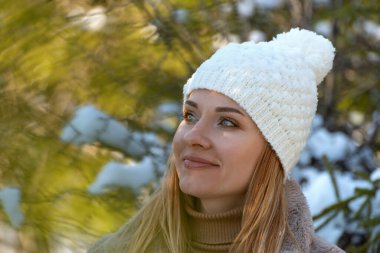 Beyaz örgü şapkalı genç bir kadının portresi Ormanda Bubo ile uzaklığa bakıyor
