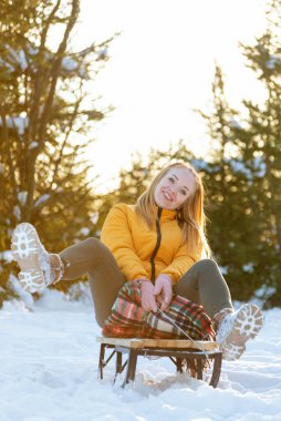 Mutlu genç bir kadın kış ormanında bir kızakta eğleniyor..