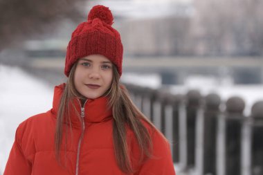 Kış manzarasının arka planında kırmızı ceketli genç bir kızın portresi.