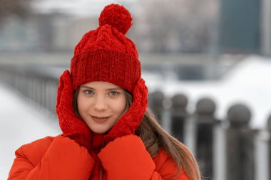 Kırmızı ceketli, örgü şapkalı ve eldivenli şirin kız kışın dışarıda poz veriyor. Moda kışı her gün arıyor.