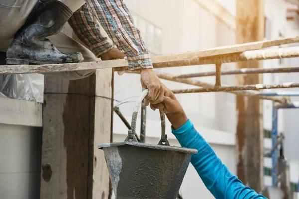 İnşaatçı müteahhit transferleri endüstri iş projesinde taze betonu karıştırıyor, inşaat alanında profesyonel istihdam olarak ıslak sıvı madde dökmeye hazırlanıyor