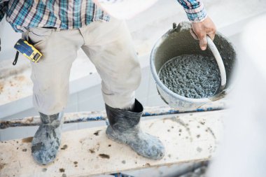 İnşaatçı müteahhitlik işi endüstri iş projesinde taze beton karıştırmak, inşaat alanında profesyonel istihdam olarak ıslak sıvı malzeme dökmeye hazır olmak