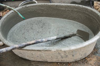 İnşaatçı müteahhitlik işi endüstriyel iş projesinde betonu karıştırıyor, inşaat sahasındaki büyük karıştırma tepsisine profesyonel istihdam olarak boru suyu döküyor