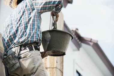 İnşaatçı müteahhitlik işi endüstriyel iş projesinde betonu karıştırıyor, inşaat alanında profesyonel istihdam olarak kolon formuna ıslak sıvı madde dökülüyor