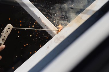 construction man is welding steel roof structure, people working in construction site concept
