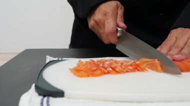 Şef taze somon filetosu kesiyor. Yemek yapmaya hazırlanıyor, suşi sashimi pişiriyor. Meşhur Asya Japon deniz ürünleri pişiriyor.