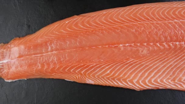黒石の表面に生の鮭の身の半分の切り身 トップビュースローモーション 有名なアジアの日本の新鮮な海の食べ物の概念 — ストック動画