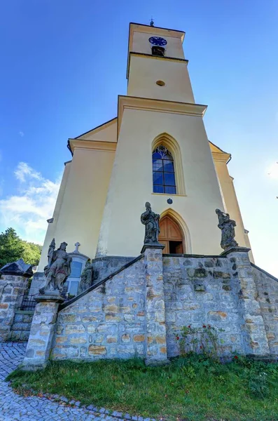石壁にバロック様式の彫像と背の高い教会の黄色の塔 — ストック写真