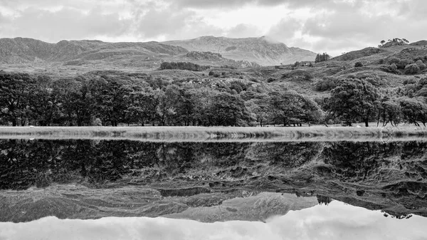 在贝德格莱特郊外的Llyn Dinas静止不动的表面上对周围山丘和森林的反思 — 图库照片