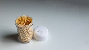 Beyaz arka planda izole edilmiş, ahşap kürdanlarla dolu şeffaf plastik bir kabın üzerine yakın çekim yapın. Küçük bir konteynırda bir sürü kürdan.