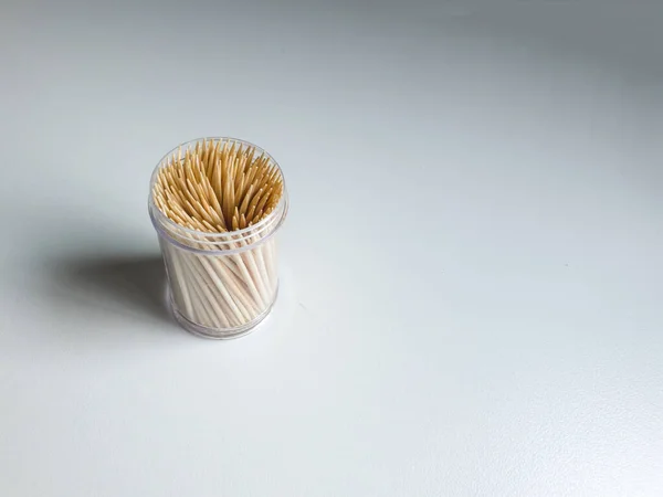 stock image Close up on a transparent plastic container filled with wooden toothpicks with the lid off isolated on a white background. Bunch of toothpicks in a small container.