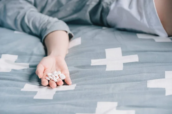 A woman takes sleeping pills to kill herself in bed.