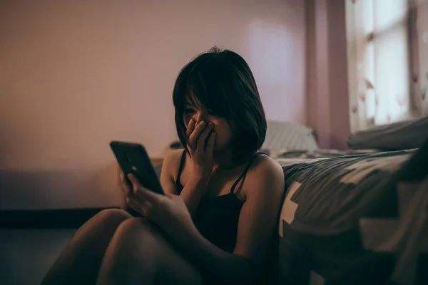 Ümitsiz bir ifadeyle telefona bakan kadın..