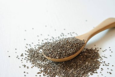 Beyaz arka planda tahta kaşıkta chia tohumları.
