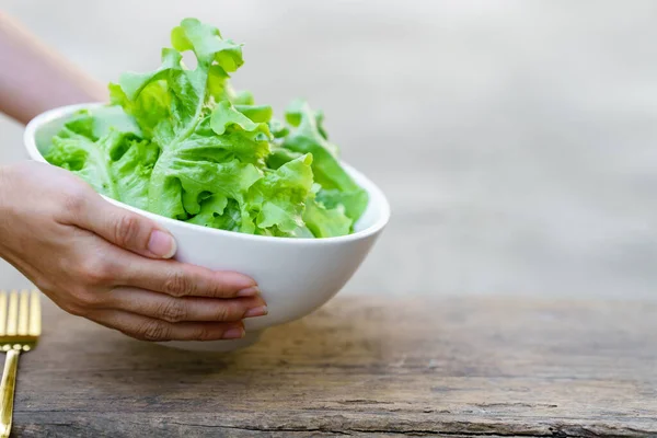 Hand holding lettuce in a white bowl. Hand holding lettuce in a white bowl.