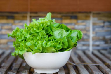 Assorted salad vegetables in white bowls on wooden table. Healthy food concept.