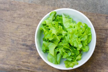 Leafy greens or lettuce in white bowls that are commonly used in salads or eaten fresh. Healthy food concept.