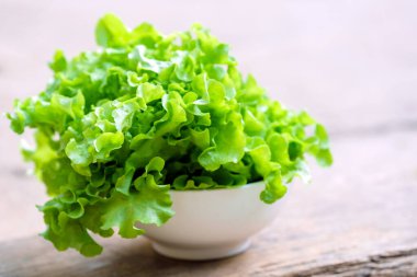 Vegetables or lettuce or green oak in a white bowl on a wooden background. Healthy food concept.