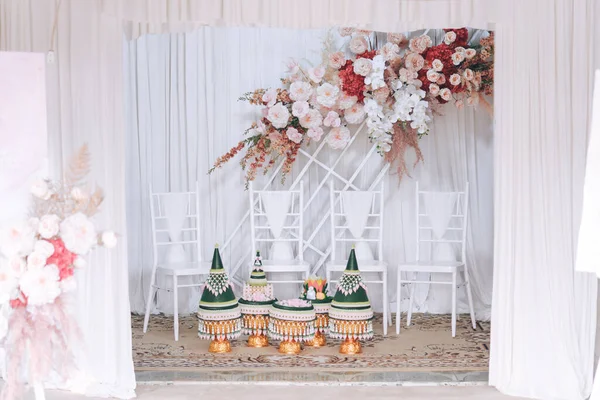 The wedding backdrop features white chairs and is decorated with delicate pink flowers. Thai wedding concept.