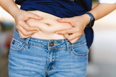 Obezite yüzünden kadının eli karnına değiyor. Sağlık hizmeti kavramı.